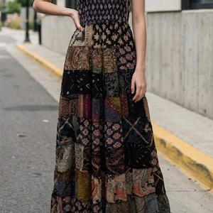 May include: A floor-length strapless maxi dress featuring a patchwork design with various dark-toned patterns including paisley, floral, and geometric motifs in shades of black, brown, gold, and deep red, constructed with a fitted bodice and a full skirt.