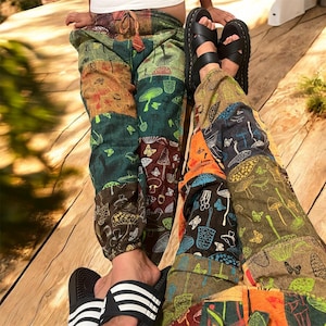 Puede incluir: Pantalones de patchwork con un patrón repetitivo de varios hongos y mariposas en tonos verdes, naranjas, marrones y azules. Los pantalones tienen una cintura elástica con cordón y puños elásticos en los tobillos.