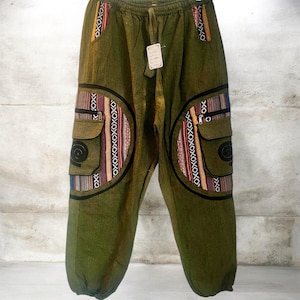 May include: Olive green pants with a drawstring waist and two cargo pockets. The pockets and side panels feature colorful woven fabric with geometric patterns in red, orange, blue, and black. The pants have a relaxed fit.