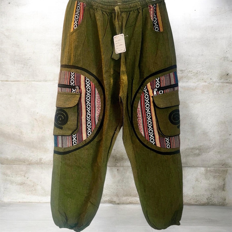 May include: Olive green pants with a drawstring waist and two cargo pockets. The pockets and side panels feature colorful woven fabric with geometric patterns in red, orange, blue, and black. The pants have a relaxed fit.