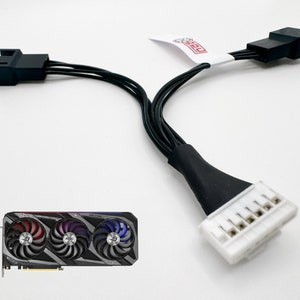 Könnte beinhalten: Eine schwarz-weiße Grafikkarte mit drei Lüftern. Die Karte hat einen schwarz-weißen Stecker mit einem weißen Etikett mit der Aufschrift "ROG". Die Karte ist mit einem schwarzen Stromkabel mit einem weißen Stecker verbunden.