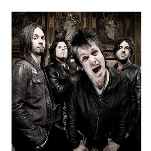 Può includere: Un gruppo di quattro uomini con giacche di pelle nera, in piedi davanti a un muro con opere d'arte religiose. L'uomo al centro indossa una giacca di pelle nera con un design di teschio e ossa incrociate e ha un tatuaggio sul collo.