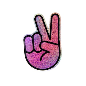 Puede incluir: Una pegatina holográfica con forma de mano haciendo el signo de la paz. La pegatina tiene un efecto de purpurina rosa y morada con un contorno negro. El texto "#BEHOUSEGANG" está impreso en la parte inferior izquierda.