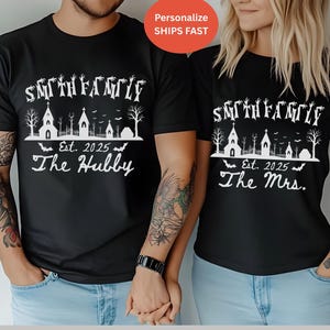Puede incluir: Camisetas negras con un diseño gráfico blanco. El diseño incluye el texto "Smith Family" sobre una escena de iglesia espeluznante, el año "Est. 2025" y las palabras "The Hubby" y "The Mrs."