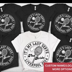 Könnte beinhalten: Sechs schwarz-weiße T-Shirts mit einem Tennis-Schläger- und Ball-Design. Der Text auf den Shirts lautet "Nicole's Last Serve Team Bride Liverpool 2024". Ein weißes T-Shirt hat den Text "It's My Last Serve The Bride Liverpool 2024".