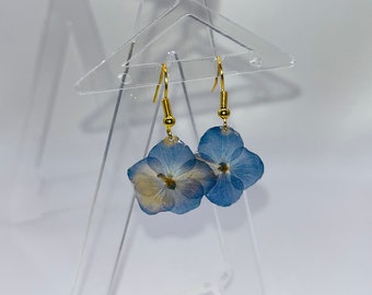 Gold-colored dangling earrings and real hydrangea flower