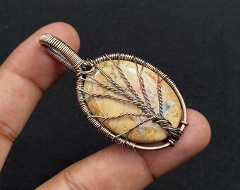 May include: Oval pendant with a light brown stone, intricately wrapped in copper wire. The wirework forms a tree-like design over the stone, creating a unique and artistic piece of jewelry.