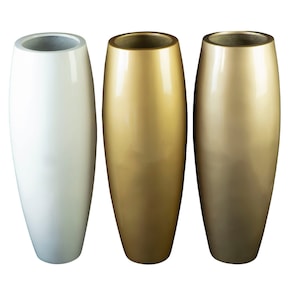 Può includere: Tre vasi in ceramica di diversi colori: bianco, oro e oro più chiaro. I vasi sono alti e sottili con una forma arrotondata.