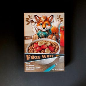 May include: A box of Foxy Woxy O's cereal featuring a cartoon fox wearing a scarf and holding a spoon. The box is brown with a rustic design and includes the text "Toasted Whole", "Foxy Woxy O's", "Vegan", "Gluten Free", "26g of Whole Grains per Serving", and "Net Wt. 12 oz (340g)".