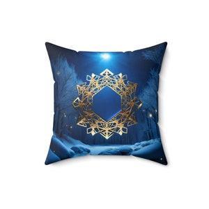 May include: Blue throw pillow with a gold snowflake design against a snowy forest background.