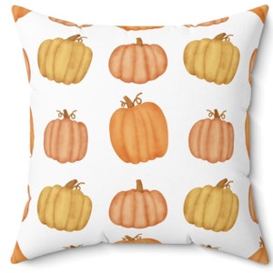 May include: A white throw pillow with a repeating pattern of orange and yellow pumpkins. The pumpkins are drawn in a watercolor style.
