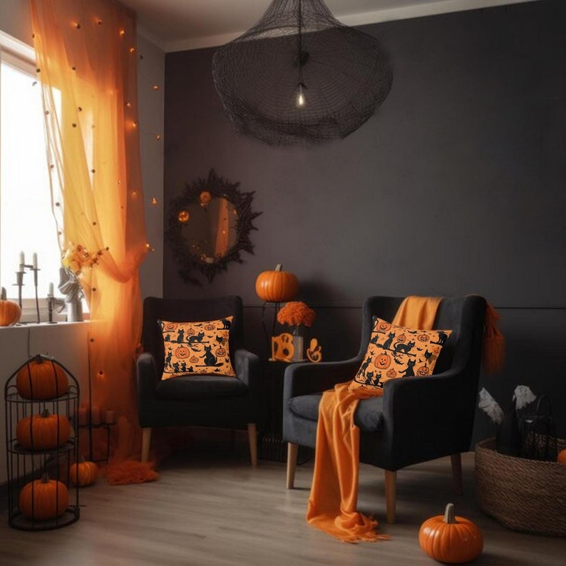 Puede incluir: Dos sillones negros con cojines naranjas con un patr&oacute;n de Halloween de gatos negros y calabazas naranjas. Los sillones est&aacute;n en una sala de estar con cortinas de gasa naranja, una l&aacute;mpara de ara&ntilde;a negra y calabazas naranjas en una mesa auxiliar.