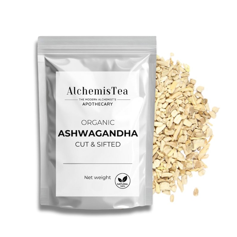 Może przedstawiać: Srebrny worek z białą etykietą, na kt&oacute;rej widnieje napis "AlchemisTea The Modern Alchemist's Apothecary Organic Ashwagandha Cut & Sifted Net weight Natural 100%". Worek zawiera jasnobrązowy, pokrojony i przesiany korzeń ashwagandhy.