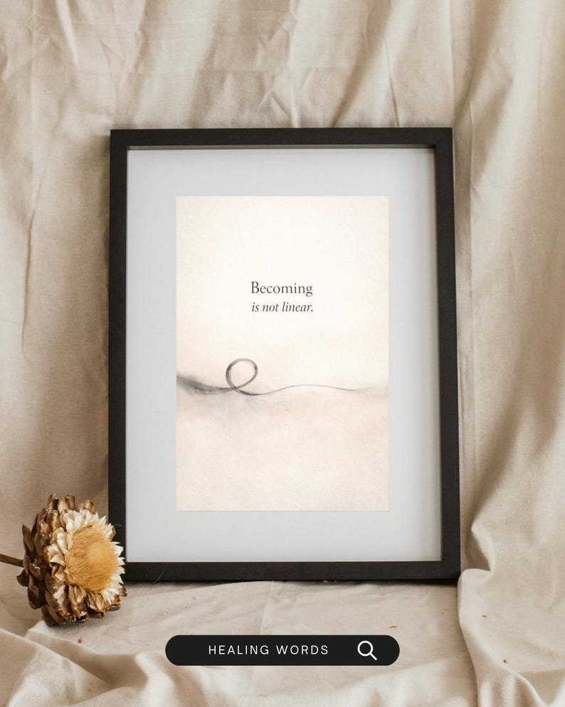 May include: A framed print with the text "Becoming is not linear." The artwork features a minimalist design with a single, looping line. The frame is black, and the print has a neutral color palette. The words "HEALING WORDS" are at the bottom.