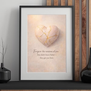 Può includere: Stampa artistica incorniciata con un cuore di pietra con crepe dorate. La stampa ha uno sfondo morbido e neutro e include il testo: "Forgive the versions of you that didn't know better - they got you here."