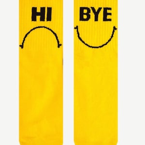 May include: A pair of yellow socks with black smiley faces and the words "HI" and "BYE" printed on them.