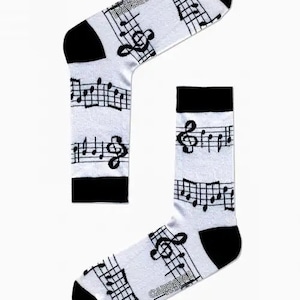 May include: A pair of white socks with a black musical note pattern and the word "CARNAVAL" printed on the socks.