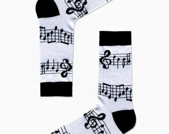 May include: A pair of white socks with a black musical note pattern and the word "CARNAVAL" printed on the socks.