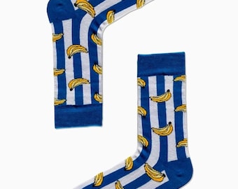Puede incluir: Un par de calcetines a rayas azules y blancas con un patrón de plátano. Los calcetines tienen el texto "CARNAVAL SOCKS" en la parte inferior.