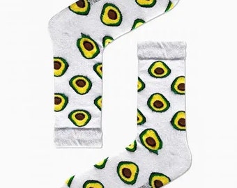 May include: A pair of white socks with a pattern of green avocados. The socks have the word "CARNAVAL" printed on them.