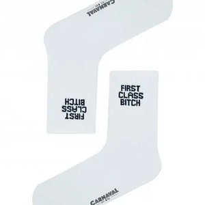 Peut inclure: Deux chaussettes blanches avec le texte "FIRST CLASS BITCH" en noir. Le mot "CARNAVAL" est imprimé en noir sur le dessus d'une chaussette. Les chaussettes sont de style décontracté.