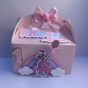 Op de afbeelding: Een roze en witte traktatiebox met een roze strik en de tekst "Khloe's Corner". De doos heeft een meisje dat ballonnen vasthoudt voor een regenboog.