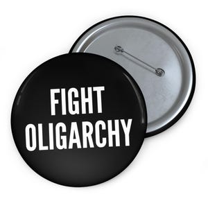 Könnte beinhalten: Ein schwarzer Knopf mit weißem Text, der "FIGHT OLIGARCHY" lautet.