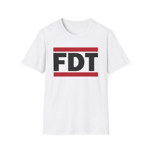 FDT shirt. This is a white tshirt with black text with the letters FDT. There are two red bars one below and one above the text. It is similar to the RUN DMC logo shirts but different enough to be distinct. The FDT on the shirt stands for Fuck Donald Trump or F Donald Trump. It is an anti Trump shirt.