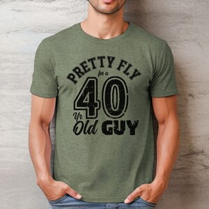 Pu&ograve; includere: Maglietta verde con una grafica nera che dice "Pretty Fly for a 40 Yr Old Guy".