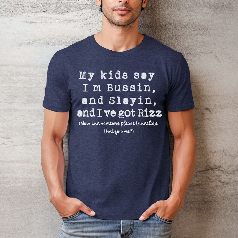 May include: Navy blue t-shirt with white text that reads "My kids say I'm Bussin, and Slayin, and I've got Rizz (Now can someone please translate that for me?)". The shirt is made of a soft material.