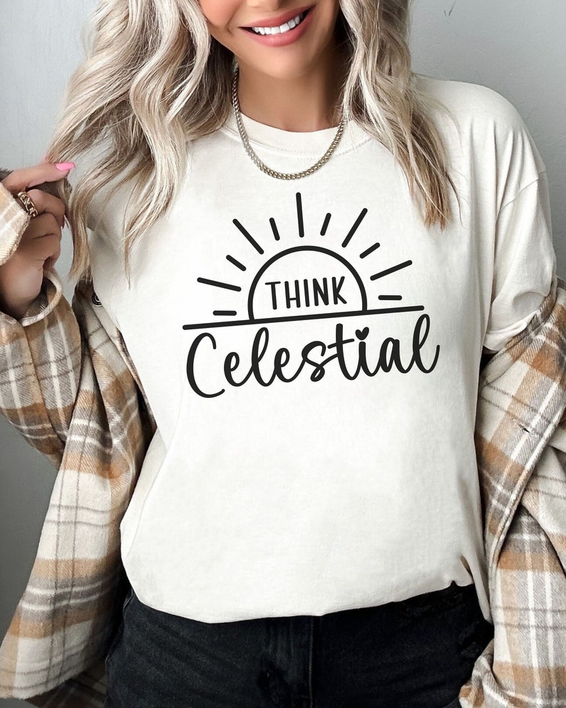 May include: White t-shirt with a black graphic of a sun with the text "Think Celestial" underneath.