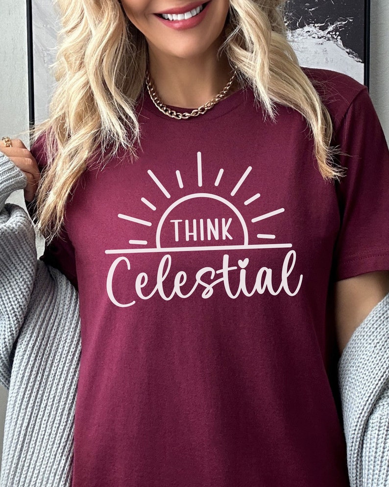 May include: A maroon t-shirt with a white graphic design of a sun with the text "Think Celestial" underneath.
