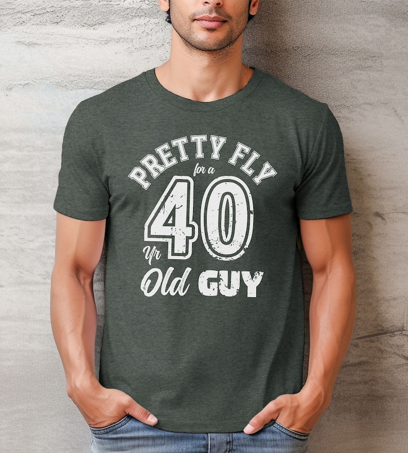 Pu&ograve; includere: Una maglietta verde scuro con una grafica bianca che dice "Pretty Fly for a 40 yr Old Guy".