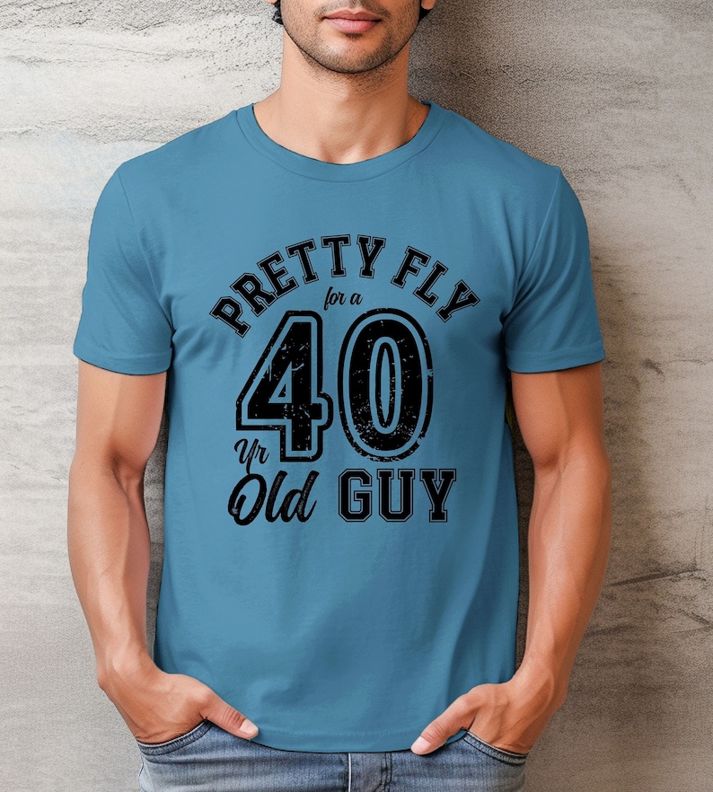 Pu&ograve; includere: Una maglietta blu con una grafica nera che dice "Pretty Fly for a 40 yr Old Guy".