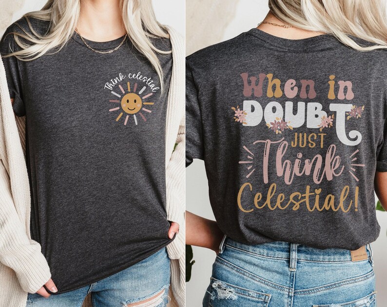 Puede incluir: Una camiseta gris oscuro con un gr&aacute;fico de sol y el texto "Think Celestial" en la parte delantera. La parte posterior de la camiseta tiene el texto "When in doubt, just think celestial!" con acentos florales.