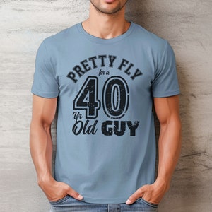 Pu&ograve; includere: Una maglietta blu con una grafica nera che dice "Pretty Fly for a 40 Yr Old Guy".