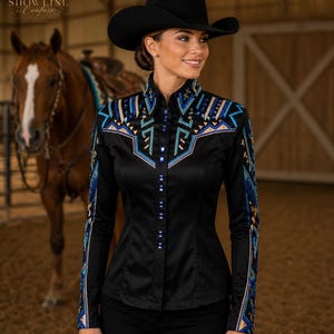 Può includere: Camicia da show equestre nera con ricami blu e oro intricati sulle spalle e sulle maniche. La camicia ha un colletto alto e una chiusura con bottoni. È visibile anche un cappello da cowboy nero. Il nome del negozio Etsy "Showline Couture" è visibile.