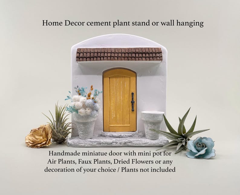 Pu&ograve; includere: Una porta in miniatura in cemento con una porta gialla e un tetto marrone, progettata per l'arredamento della casa. Include un piccolo vaso per piante aeree, piante finte o fiori secchi. Il testo recita: "Home Decor cement plant stand or wall hanging" e "Handmade miniature door with mini pot for Air Plants, Faux Plants, Dried Flowers or any decoration of your choice / Plants not included."