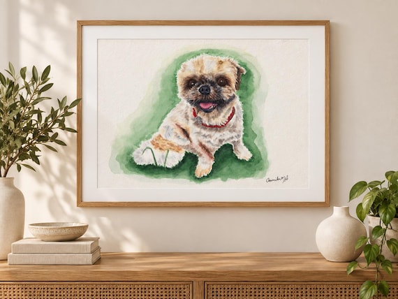 A framed watercolor painting of a small, light-colored dog with a dark muzzle and a red collar. The dog is depicted sitting against a soft, blended green background. The artwork is signed in the bottom right corner in black ink.