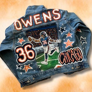 May include: A blue denim jacket with the name "OWENS" and the number "36" painted on the back. The jacket also features a painting of a football player in a Chicago Bears uniform, along with the words "CHICAGO" and several stars.