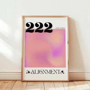 May include: A framed print with a pink and purple gradient background. The number 222 is printed in black at the top of the print. The text "Angel Numbers" is printed in black below the number. The text "ALIGNMENT" is printed in black at the bottom of the print.
