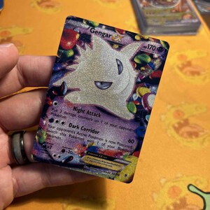 May include: A holographic Gengar EX Pokémon trading card. The card features a white Gengar with purple accents and the number 170. The card has the text "Night Attack" and "Dark Corridor".