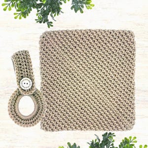 May include: A beige crochet kitchen towel and matching hanging loop. The towel is square with a tight stitch pattern. The loop has a button that reads "handmade". The items are made of a soft, textured yarn.