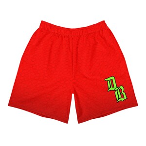 May include: Red athletic shorts with a subtle pattern and an elasticated waistband. The shorts feature a neon green and black logo on the lower right leg. These shorts are designed for comfort and performance.