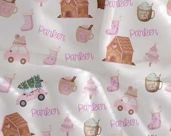 May include: A white baby blanket with a pink and brown gingerbread house, Christmas tree, and car pattern. The blanket is personalized with the name "Parker" repeated throughout the design.