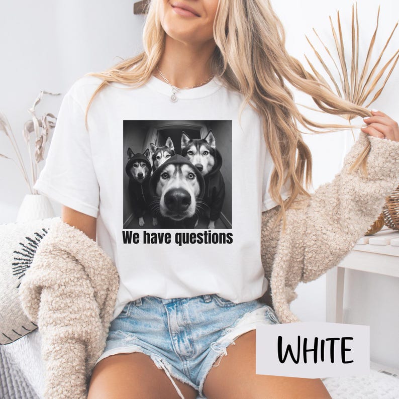 May include: White t-shirt with a black and white image of four Huskies in hoodies, with the text "We have questions". The t-shirt is a crew neck style.