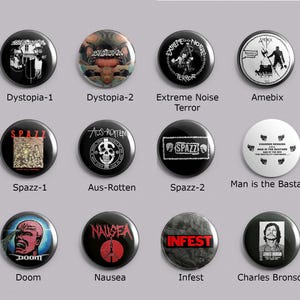 May include: A collection of black button pins with various band names and graphics. The pins feature text such as "Dystopia," "Spazz," and "Infest," along with illustrations of skulls, figures, and other designs. The pins are round and have a glossy finish.