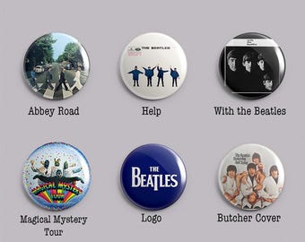 May include: A set of six circular pin-back badges featuring The Beatles imagery. Designs include the Abbey Road crossing, the Help album cover, With the Beatles, Magical Mystery Tour, a blue badge with The Beatles logo, and the Yesterday and Today cover.