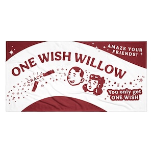 May include: A rectangular beach towel featuring a maroon and white design. The text reads ONE WISH WILLOW, AMAZE YOUR FRIENDS!, CRACK, and You only get ONE WISH. The graphic includes two cartoon faces and small star shapes on a white background.