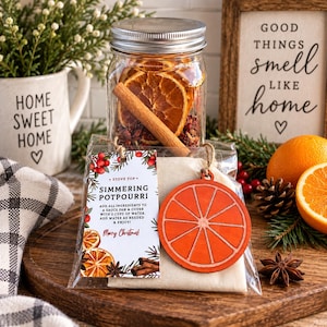May include: A clear glass jar filled with dried orange slices and cinnamon sticks, accompanied by a small bag of simmering potpourri. The attached tag reads: STOVE TOP SIMMERING POTPOURRI, ADD ALL INGREDIENTS TO A SAUCE PAN & COVER WITH 2 CUPS OF WATER.